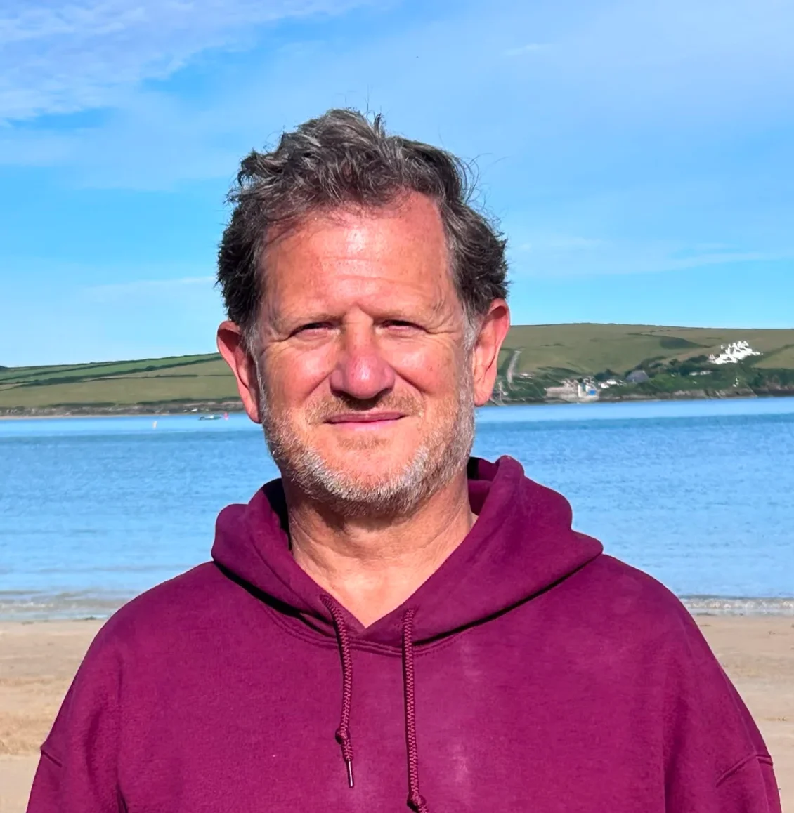 Headshot Portrait of Freddie de Lisle standing by the sea.